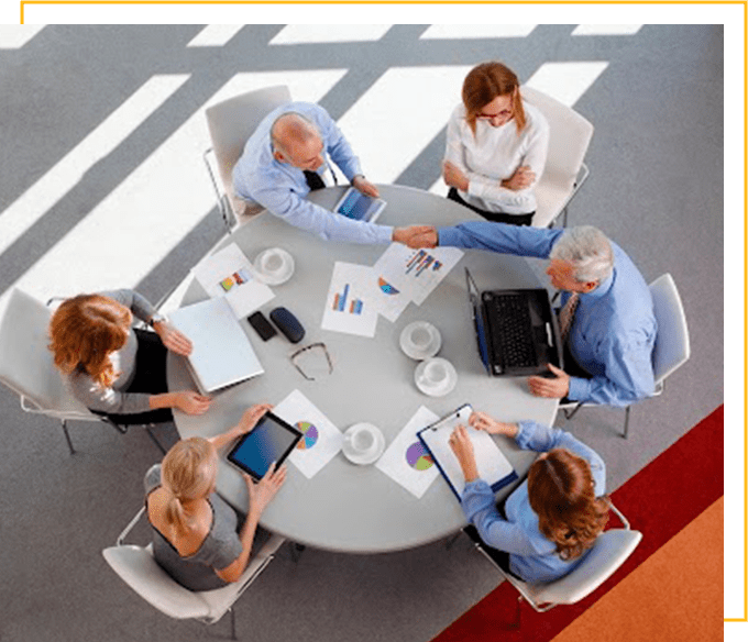 High angle view of business team sitting around the desk and shaking hands.